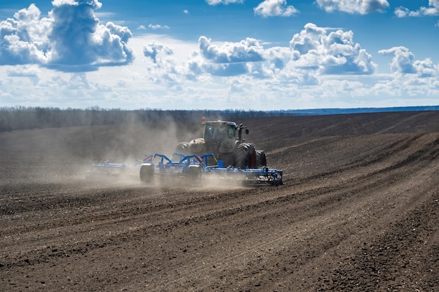 Tracteur avec semoir sur le terrain au début du printemps