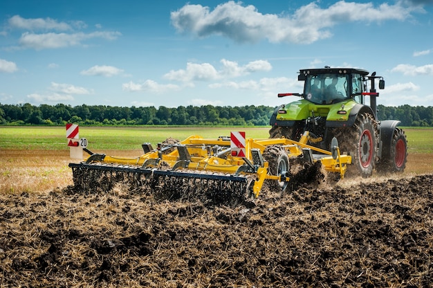 Le tracteur tire un cultivateur à disques, le système de travail du sol sur le terrain se prépare pour la nouvelle saison