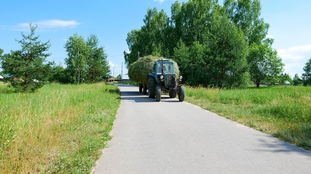 Le tracteur transporte le foin dans le village.