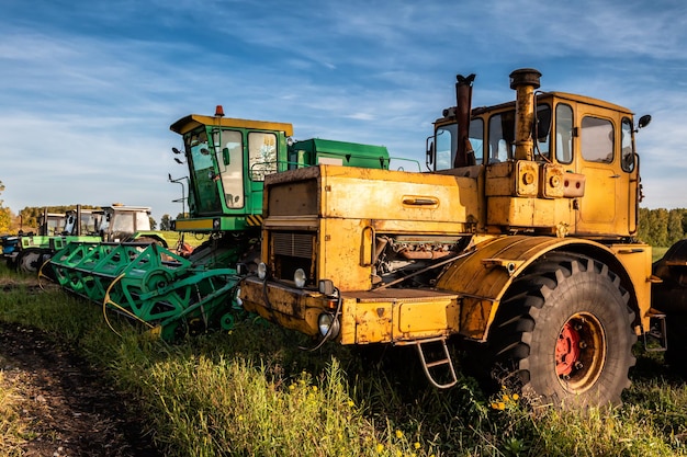 Tracteurs à roues et moissonneuse-batteuse debout dans une rangée sur un champ agricole