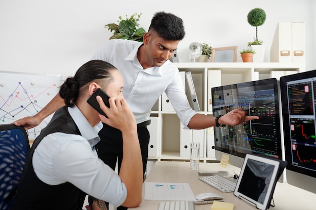 Trader pointant sur un écran d'ordinateur et montrant que le cours de l'action est tombé à son collègue