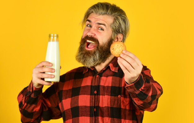 Tradition du petit-déjeuner Hipster heureux manger un dessert aux biscuits Combinaison délicieuse Recette de biscuits faits maison Biscuit au lait et sucré Délicieux comme dans l'enfance Homme barbu mature boit du lait avec des biscuits