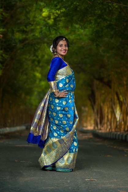 Photo traditionnelle indienne belle jeune fille en saree posant à l'extérieur du parc