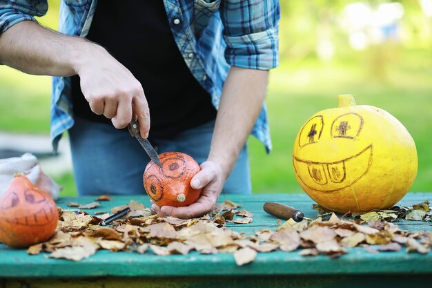 Traditions d'automne et préparatifs de la fête d'Halloween. Une maison dans la nature, une lampe faite de citrouilles se découpe à table.