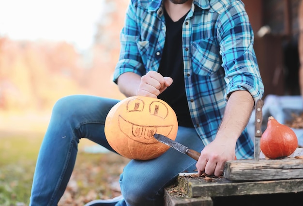 Traditions d'automne et préparatifs de la fête d'Halloween. Une maison dans la nature, une lampe faite de citrouilles se découpe à table.