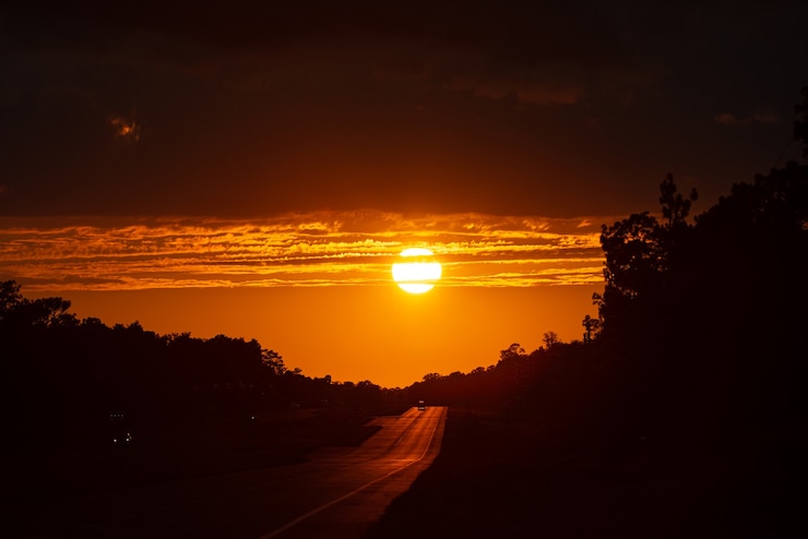 Photo trafic routier au coucher du soleil. route avec barrière de sécurité en métal. voitures sur l'asphalte sous le ciel nuageux.