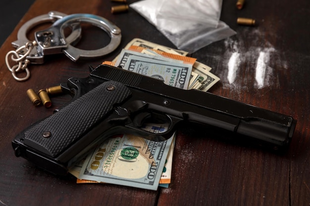 Trafic et trafic de drogue Menottes pistolet argent et cocaïne sur fond de table en bois