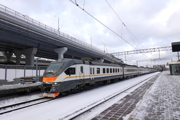 Photo un train de banlieue régional arrive à la gare par une journée d'hiver nuageuse.