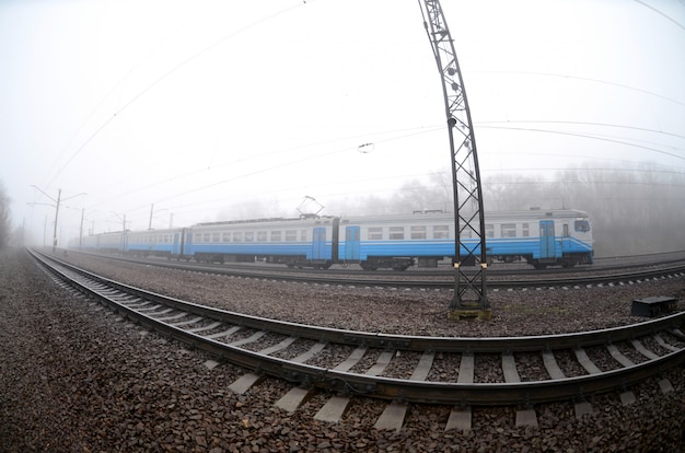 Le train de banlieue ukrainienne se précipite le long de la voie ferrée par un matin brumeux