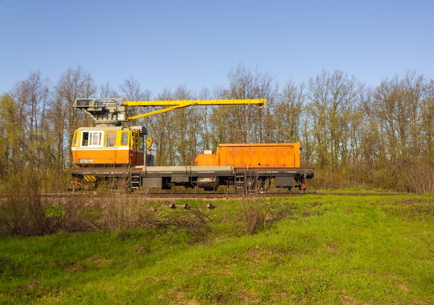 Train d'entretien jaune garé sur des rails utilisés pour l'entretien des chemins de fer