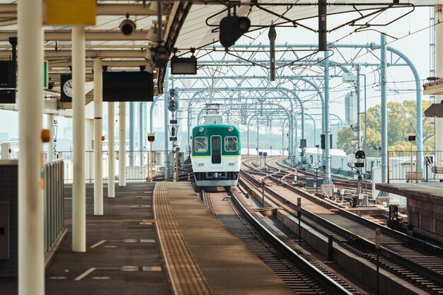 Train ferroviaire électrique à structure métallique et voies arrivée à la gare de Kyoto