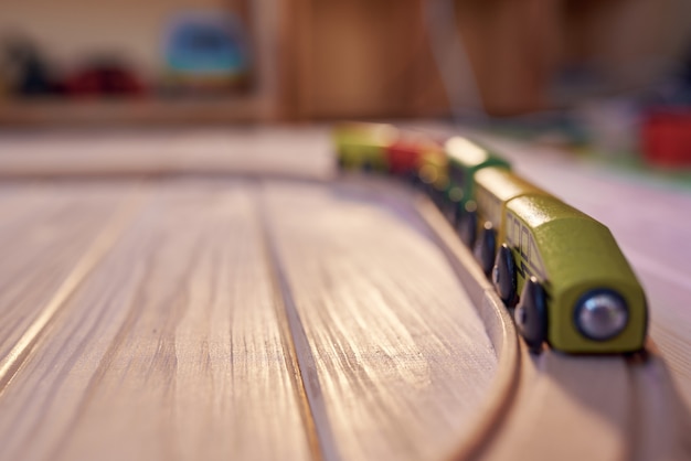 Train jouet en bois sur une piste avec chambre d'enfants défocalisé en toile de fond