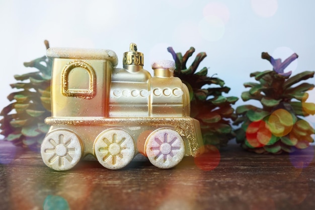 Train jouet doré pour enfants Cônes peints à la gouache verte comme arbres de Noël Nouvel An ou carte de Noël Glaçons et neige dans le train Arrière-plan bokeh festif Décorations de Noël