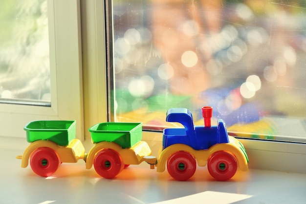 Train jouet en plastique avec remorques sur le rebord de la fenêtre