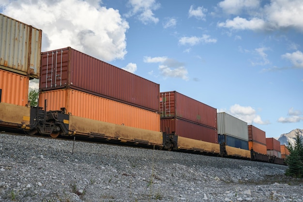 Train long fret passant avec le chargement de conteneurs sur le chemin de fer dans la vallée à Calgary Canada