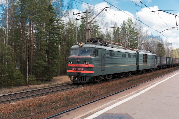 Train de marchandises tracté par une locomotive électrique en arrière-plan de la forêt