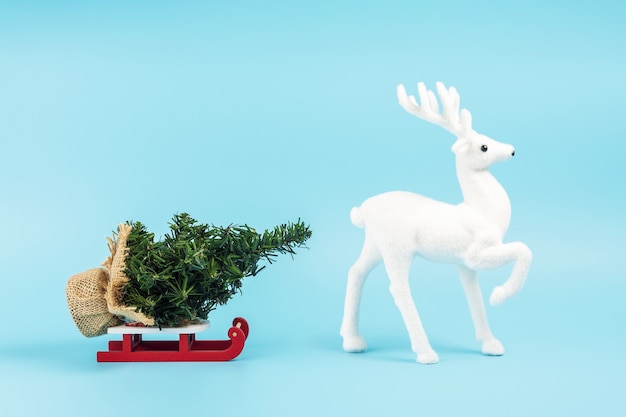 Traîneau du Père Noël avec arbre de Noël et renne blanc sur bleu