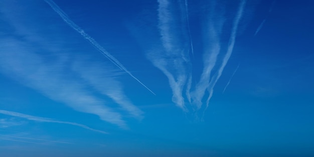 Traînée d'avion contre le ciel bleu avec des nuages blancs Sentier de condensation de l'avion à réaction Lignes de nuages faites d'avions