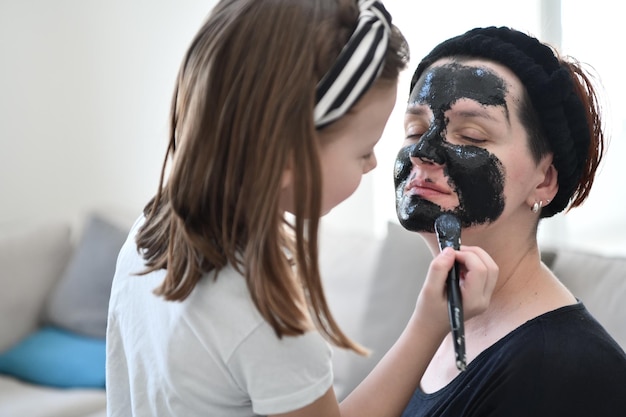 Traitement de beauté familial à domicile pendant la pandémie de coronavirus, séjour en quarantaine à domicile. La mère et la petite fille font un masque facial.