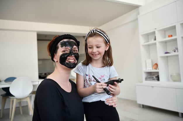 Traitement de beauté familial à domicile pendant la pandémie de coronavirus, séjour en quarantaine à domicile. La mère et la petite fille font un masque facial.