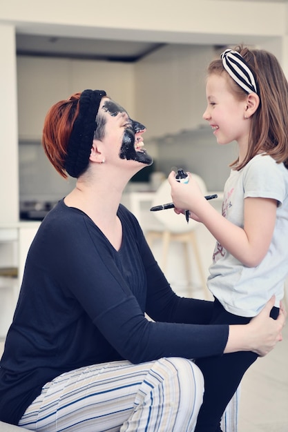 Traitement de beauté familial à domicile pendant la pandémie de coronavirus, séjour en quarantaine à domicile. La mère et la petite fille font un masque facial.