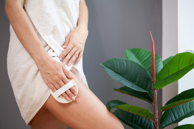 Traitement de la cellulite bras de femme tenant une brosse sèche en haut de sa jambe