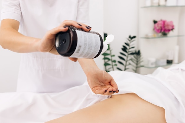 traitement à la crème sur les jambes de la femme avec une lotion hydratante empêchant la peau sèche sur les parties du corps féminin en gros plan