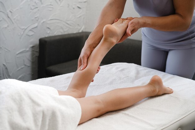 Traitement de massage des pieds pour enfants par un massothérapeute professionnel dans une station balnéaire Concept de soulagement du stress et de soins de santé Close-up Personne de croissance et de flexibilité