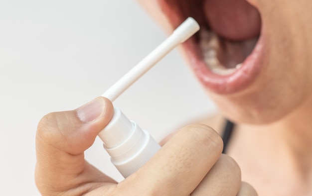 traitement des maux de gorge.gros plan de la bouche grande ouverte de la femme et pulvérisation pour la douleur,cou intérieur rouge.virus