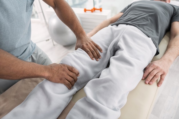 Traitement professionnel. Vue de dessus des mains mâles faisant un massage médical pour le patient