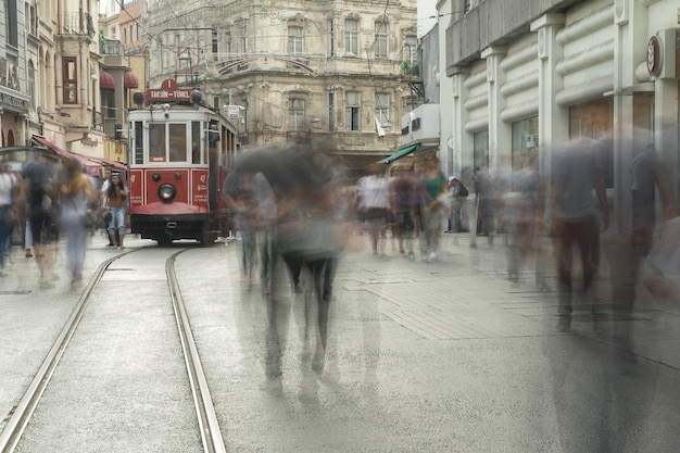 Tram passant par les gens de la place Taksim en silhouette