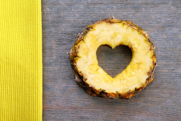 Tranche d'ananas avec coupe en forme de coeur sur fond de bois