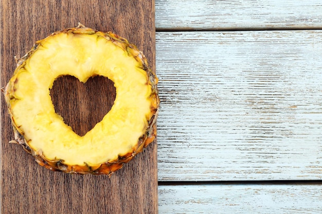 Tranche d'ananas avec coupe en forme de coeur sur fond de bois