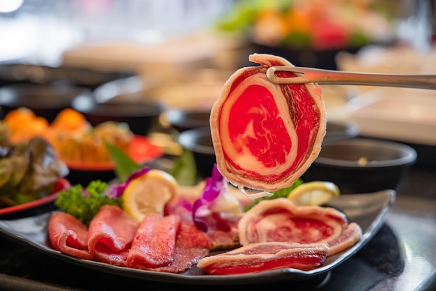 Photo tranche de bœuf de qualité supérieure avec pinces en acier inoxydable dans le restaurant buffet