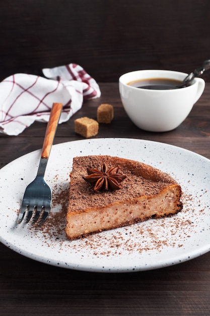 Tranche de casserole de caillé de chocolat sur une assiette, une portion de gâteau au chocolat et café. Table rustique en bois foncé.