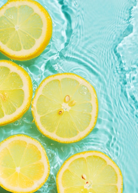 Tranche de citron sous l'eau ou dans l'eau avec des éclaboussures et des gouttelettes vue de dessus à plat sur fond bleu