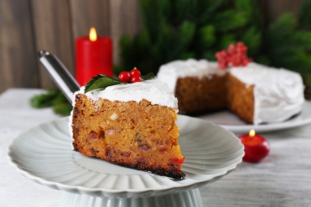 Tranche de crème recouverte de gâteau avec décoration de Noël sur table, sur une surface murale en bois