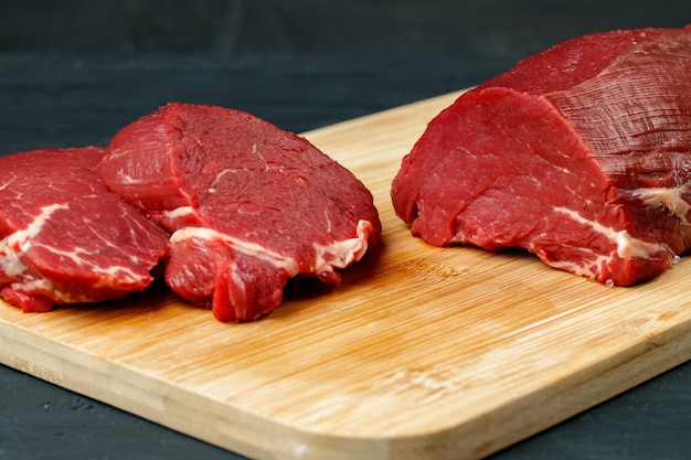 Tranche de filet de boeuf cru sur planche de bois