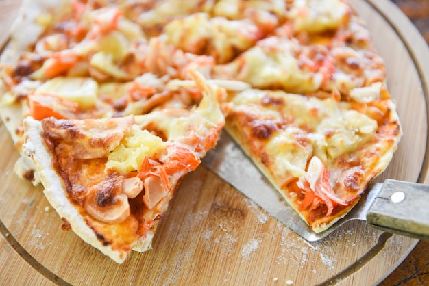 Photo tranche de fromage pizza sur un plateau en bois et servi sur une table en bois