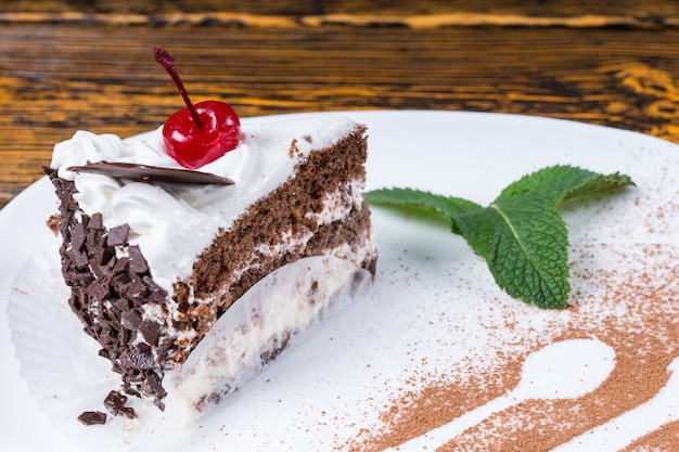 Tranche de gâteau au chocolat crémeux fraîchement cuit servi sur une assiette avec des détails décoratifs d'une cuillère et d'une fourchette en poudre de chocolat dans un restaurant gastronomique