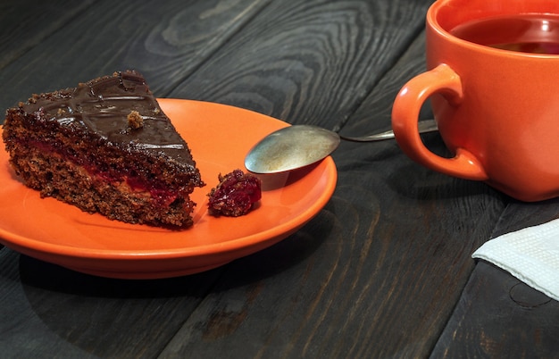 Tranche de gâteau au chocolat dans une assiette et une tasse de thé sur une table vintage pendant le petit déjeuner