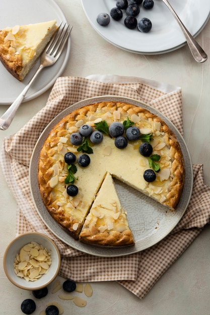 Tranche de gâteau au fromage avec des flocons de myrtilles et d'amandes avec des couverts sur une vue de dessus de fond clair