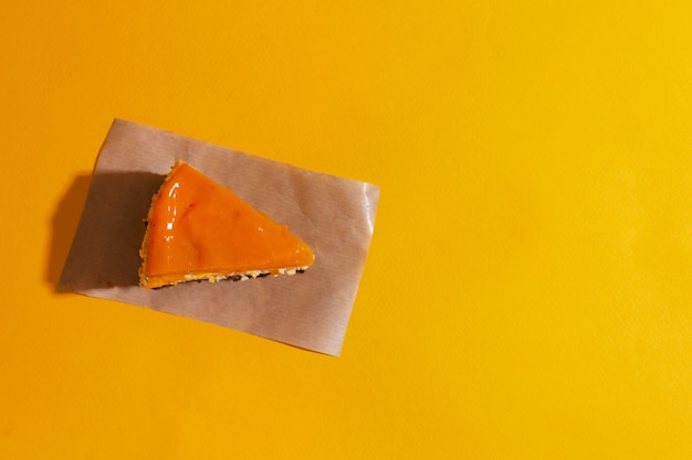 Tranche de gâteau au fromage à la mangue avec garniture d'argousier sur fond orange transparent