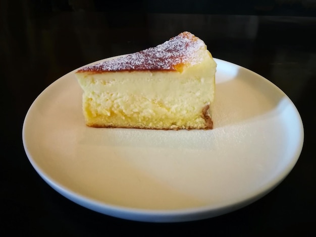Tranche de gâteau au fromage en marbre ordinaire sur plaque blanche et fond sombre