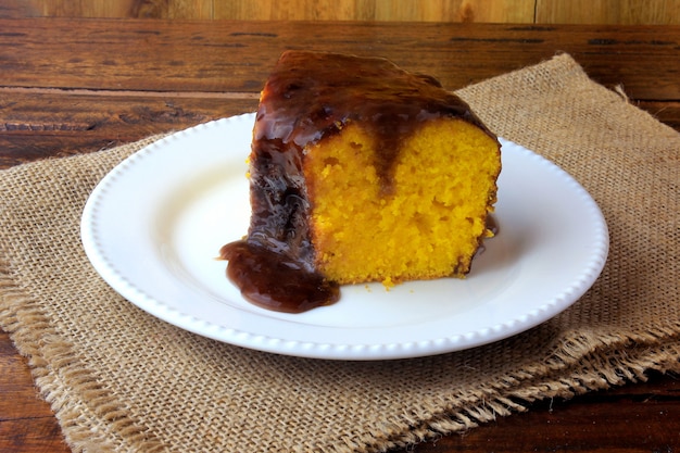 Tranche de gâteau aux carottes enrobé de chocolat sur une assiette en céramique blanche