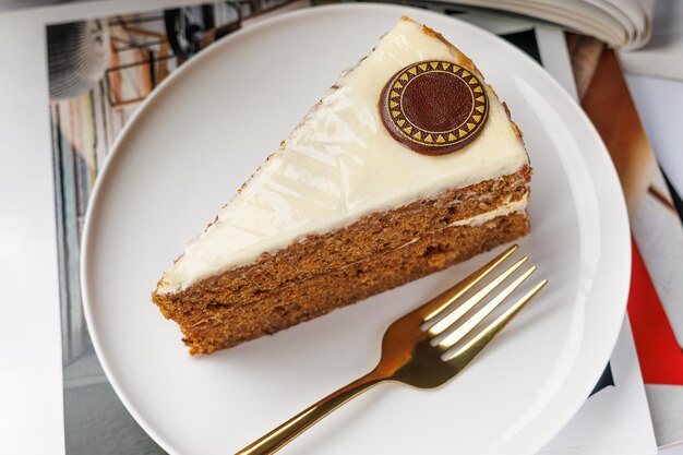 Photo une tranche de gâteau à la carotte sur une assiette blanche avec une fourchette dorée