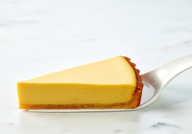 Tranche de gâteau à la mangue végétalienne fraîche sur une table de cuisine légère