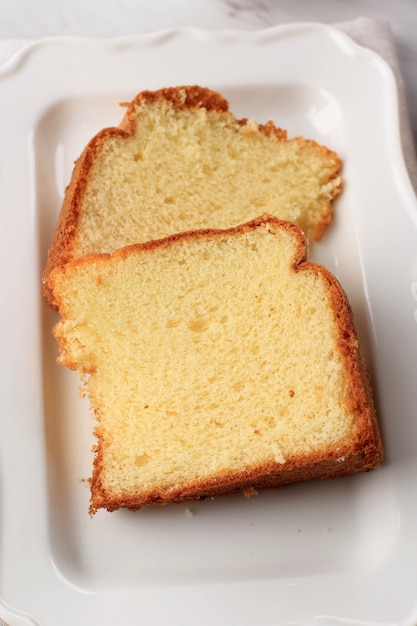 Tranche de gâteau en mousseline de soie à la vanille moelleux ou gâteau éponge sur une assiette en bois, servi avec du thé et du miel