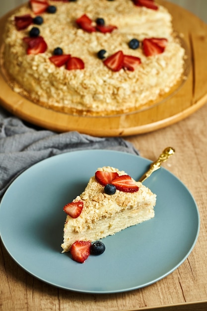 Tranche de gâteau Napoléon maison sur assiette. Fond en bois