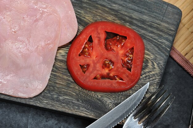 Une tranche de jambon et une tranche de tomate